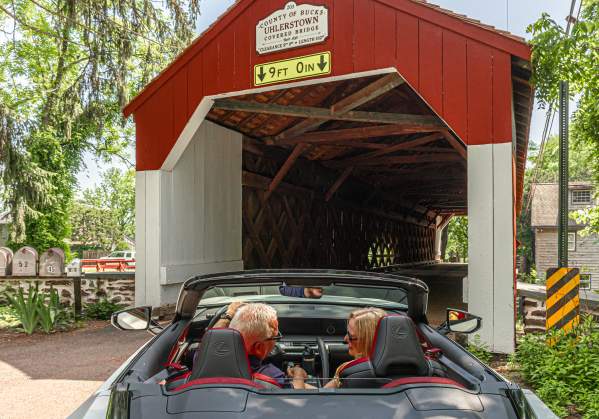 a couple drives through a covered bridge