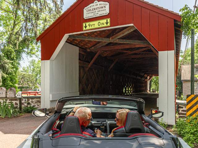 a couple drives through a covered bridge