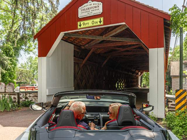 a couple drives through a covered bridge