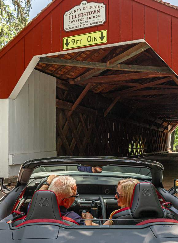 a couple drives through a covered bridge