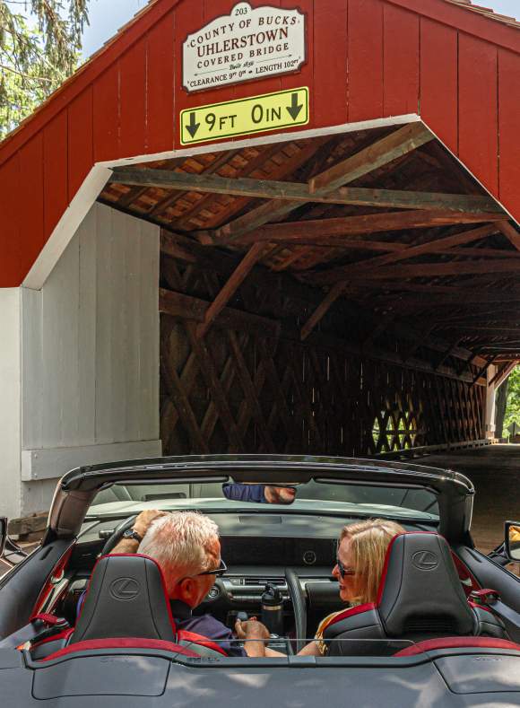 a couple drives through a covered bridge