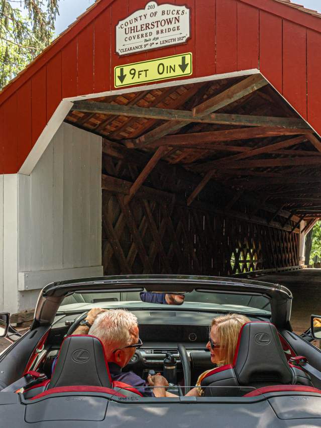 a couple drives through a covered bridge