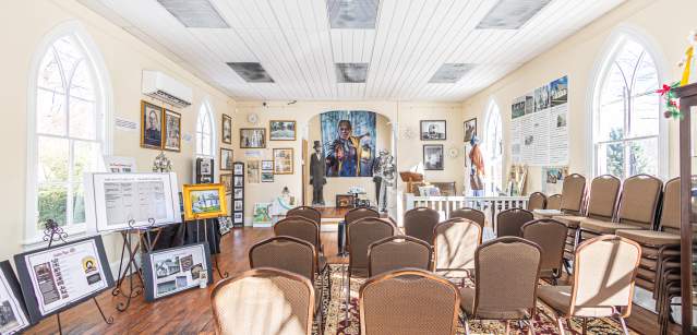 Interior of Gather Place in Bucks County featuring arranged chairs, framed photographs, historical displays, and a mural at the front of the room.