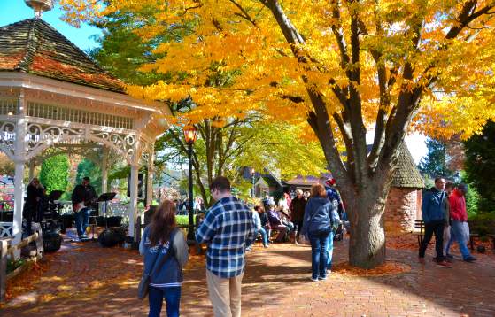 Autumn gazebo with colorful fall leaves and people enjoying music.