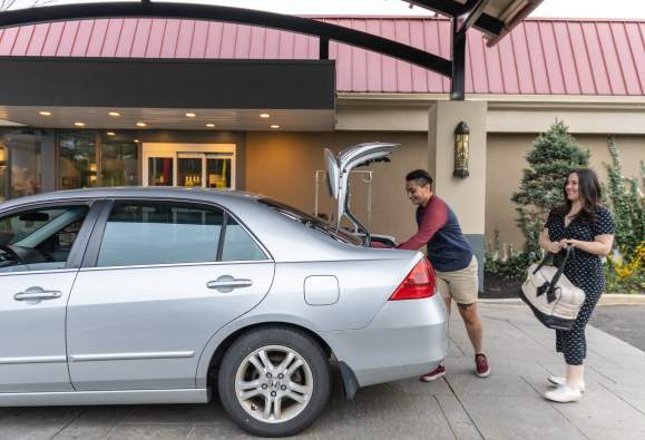 two people take their suitcases out of the car