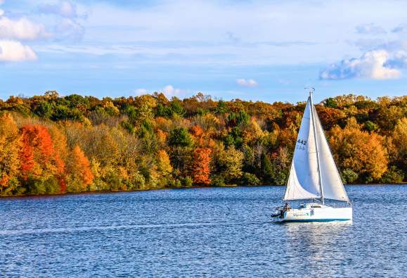 Sailboat on the river during peak fall foliage