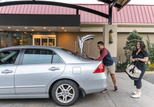 two people take their suitcases out of the car