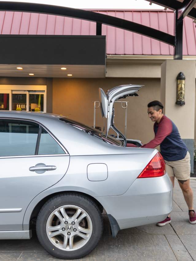 two people take their suitcases out of the car