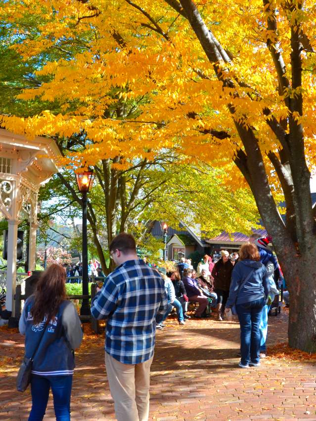 Autumn gazebo with colorful fall leaves and people enjoying music.