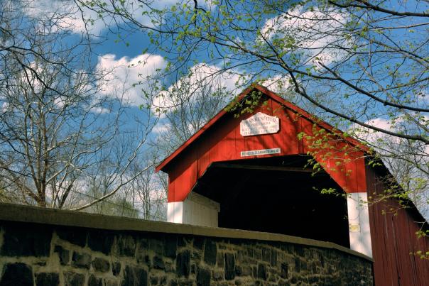 The bright red paint of Frankenfield Covered Bridge shines bright among the greens on a spring day. The bridge is one of 12 remaining covered bridges in Bucks County.