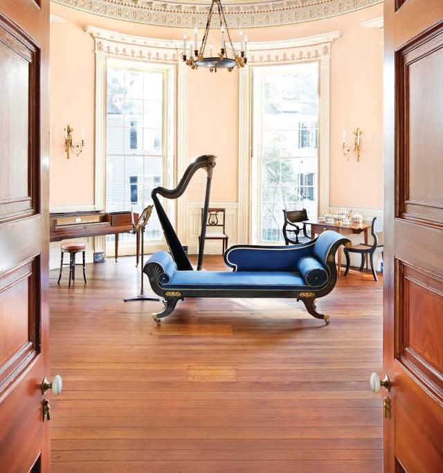 A harp, a piano, and a blue chair are arranged in a room, highlighting a serene musical setting.