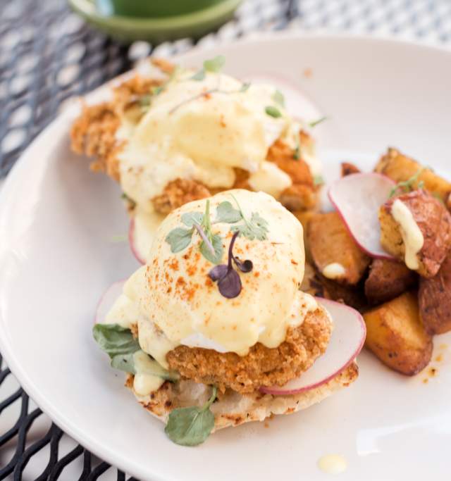A white plate filled with golden fried potatoes next to fried chicken in hollandeisse sauce