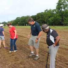 Tamping down soil after seeds have been planted.