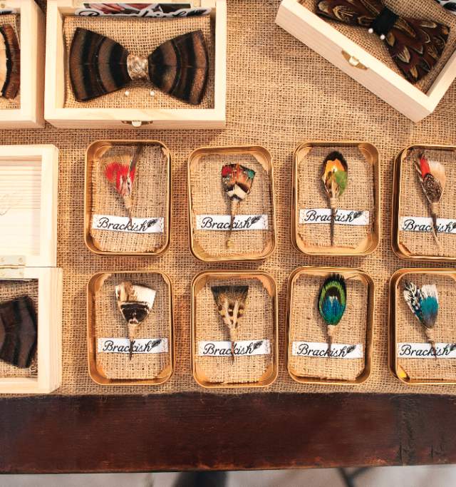 A collection of wooden boxes showcasing an assortment of colorful feathers in various shapes and sizes.