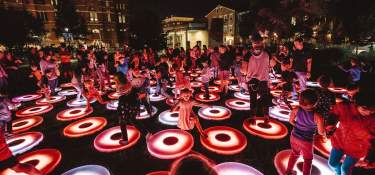 A crowd of people dancing on lighted up circles at BLINK Cincy