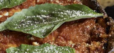 A deep dish, Chicago style pizza with fresh basil on top.