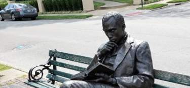 Image is of the bronze statue of James Bradley sitting on a bench, reading a book.