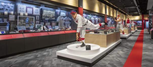 A statue of a pitcher in action stands in front of a wall of display cases.