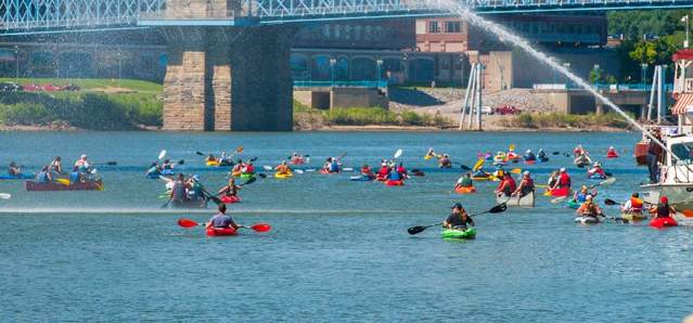 A large group of kayaks paddle under the Roebling Suspension Bridge in Covington, Kentucky during Paddlefest.