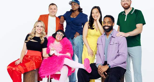 A group of 7 colorfully dressed individuals pose in front of the camera.