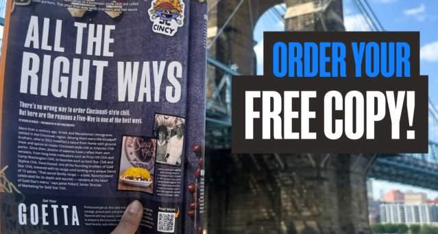 Someone holding up a 2026 Official Visitors Guide in front of the Roebling Bridge.