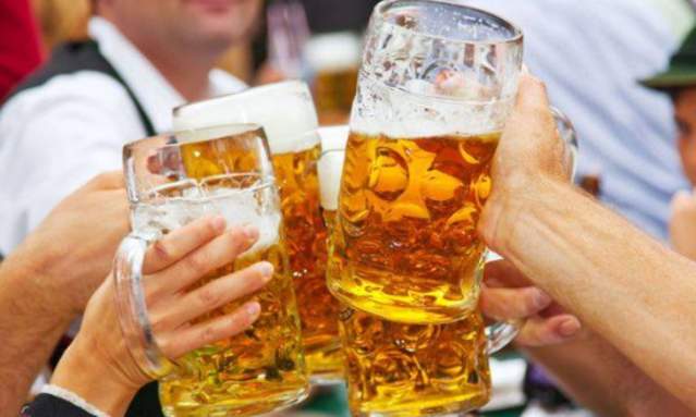 Four hands holding large glass steins of beer at Newport Oktoberfest
