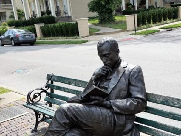 Image is of the bronze statue of James Bradley sitting on a bench, reading a book.