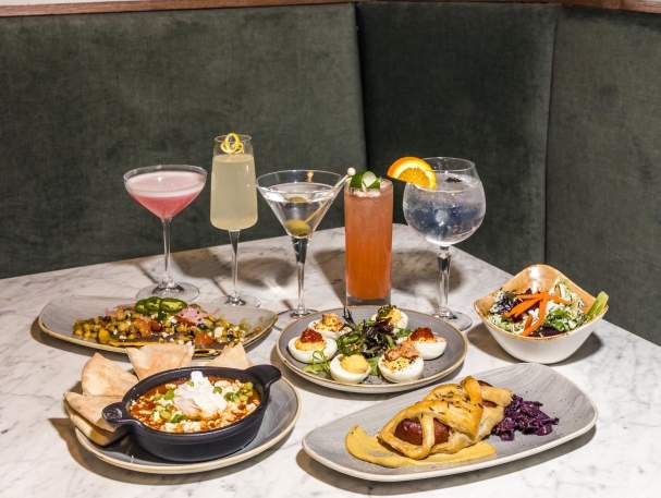 A table with several tapas plates and cocktails.
