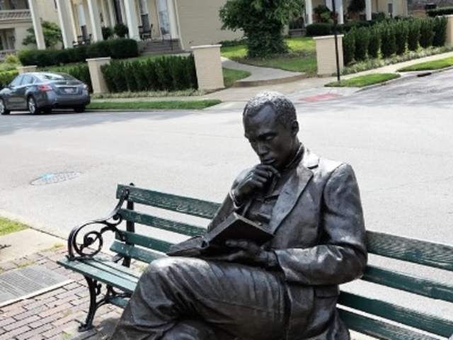 Image is of the bronze statue of James Bradley sitting on a bench, reading a book.