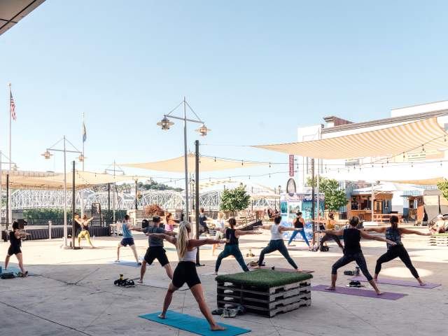 A group of attendees participate in an outdoor yoga session at Newport on the Levee.