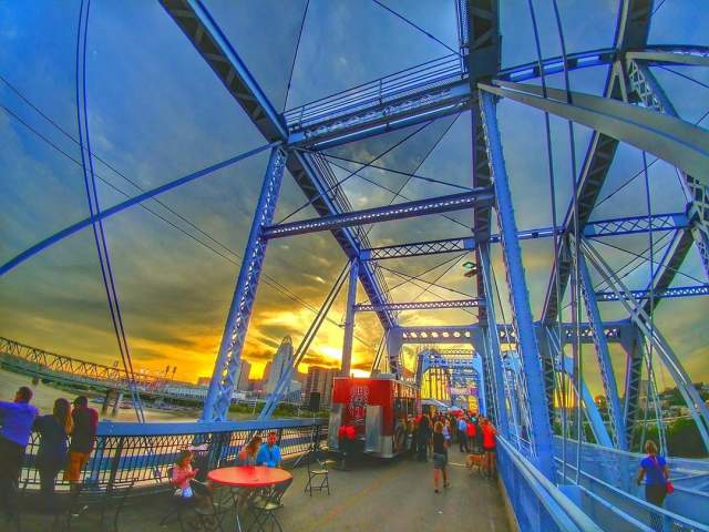 Tables and food vendors set up on the Purple People Bridge at sunset.