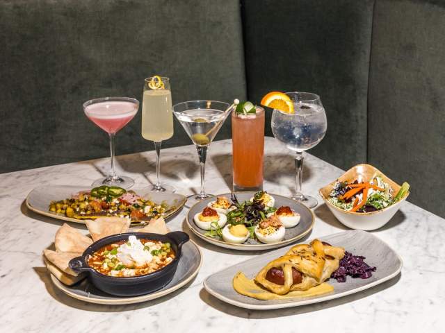 A variety of cocktails among various small plates of tapas.