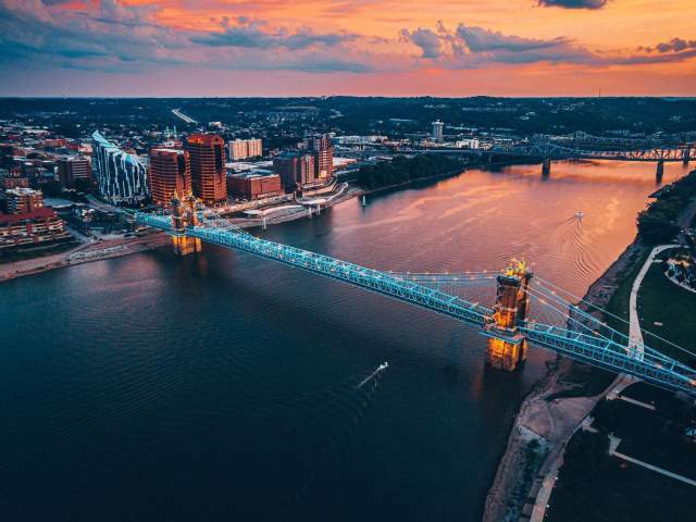 Sunset in the background over the Ohio river with the John A. Roebling Suspension bridge spanning from NKY to Cincy