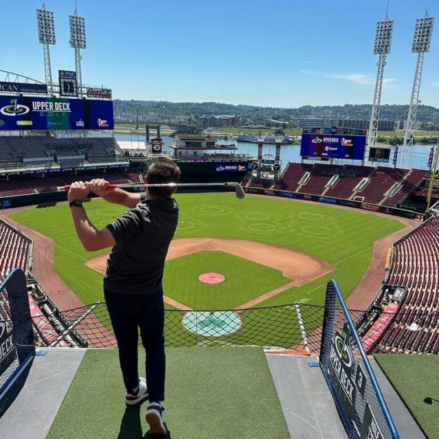 A man swings a golf club at Great American Ball Park