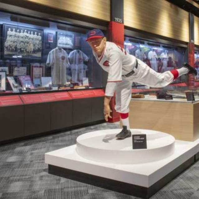 A statue of a pitcher in action stands in front of a wall of display cases.