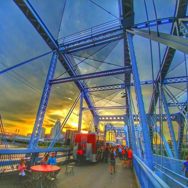 Tables and food vendors set up on the Purple People Bridge at sunset.