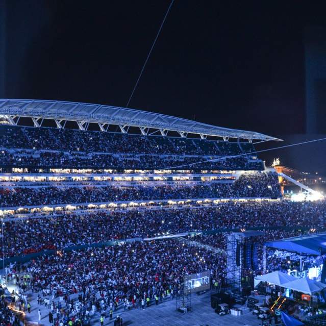 A massive crowd fills Paycor Stadium with a stage set up for CMF in the foreground, while the background is a dark night sky with stadium lights.