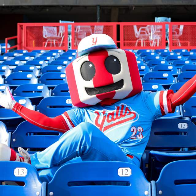 An anthropomorphic version of the famous red and white striped Florence, KY watertower, dressed in a blue and red Florence Y'alls uniform. It sits in the stadium seats arms stretched wide.