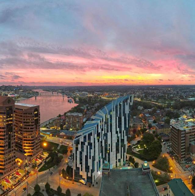 The sky glowing pink and gold with a sunrise behind the skyline of Covington, Ky. with Cincinnati, Ohio in the background
