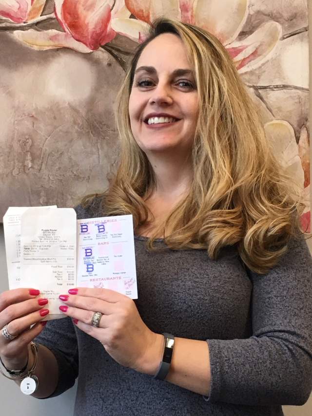 A blonde woman holding a B-Line Line Guide in front of a painting of flowers