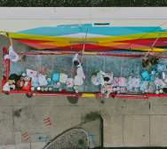 An aerial view of a crew painting a mural on the side of a building