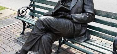 Image is of the bronze statue of James Bradley sitting on a bench, reading a book.