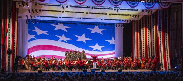 The Cincinnati Symphony Orchestra performs onstage with American flag decor as a backdrop