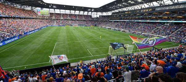 Fans wearing orange and blue sit inside the FC Cincinnati soccer stadium