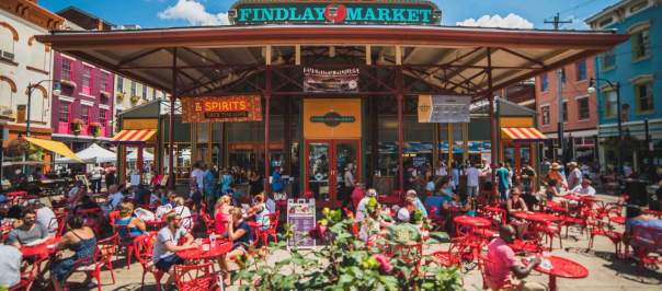 Exterior of Findlay Market showing the sign. Many bistro tables fill the patio for people to sit and eat.