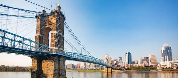 The Roebling Suspension bridge leading to downtown Cincinnati's skyline under a sunny blue sky