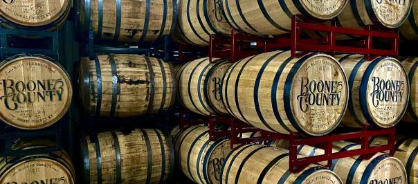 Bourbon barrels stamped with Boone County and stacked on red shelves