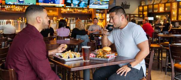 two men enjoying beer and food at 859 taproom