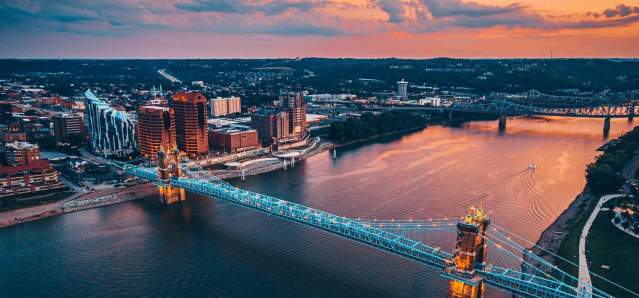 Sunset in the background over the Ohio river with the John A. Roebling Suspension bridge spanning from NKY to Cincy