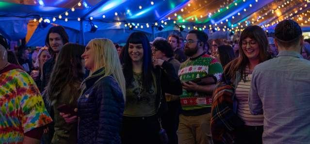 A group of people, watching the stage, smiling, and having a good time.